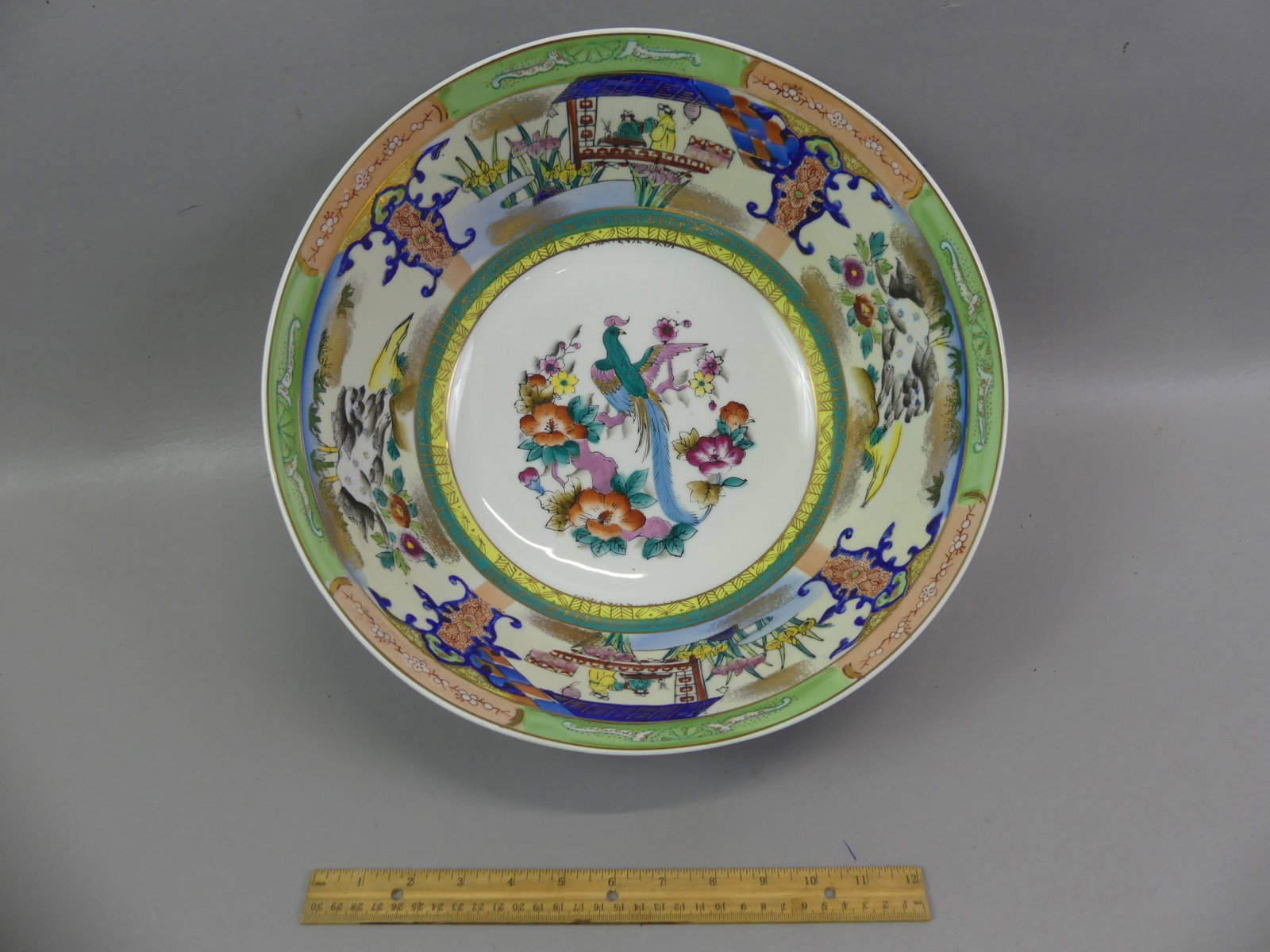 OLD CHINESE PUNCHBOWL - LANDSCAPES & BIRD: Large old Chinese ceramic punchbowl with polychromed decoration of exotic bird in center surrounded by genre scenes and landscapes. Unsigned, early 20th century. 14 in diameter and 6.5 in deep. VG