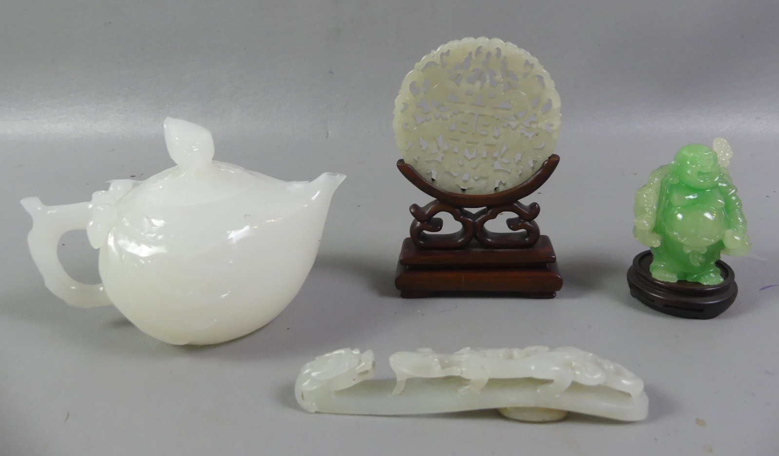 LOT OF CHINESE JADE ITEMS: Lot of 4 old Chinese jade items: White jade teapot 5.5 in; white jade belt buckle with dragons; 3 in diam. white jade reticulated disc on wood stand; 2 in green jade figure of buddha.