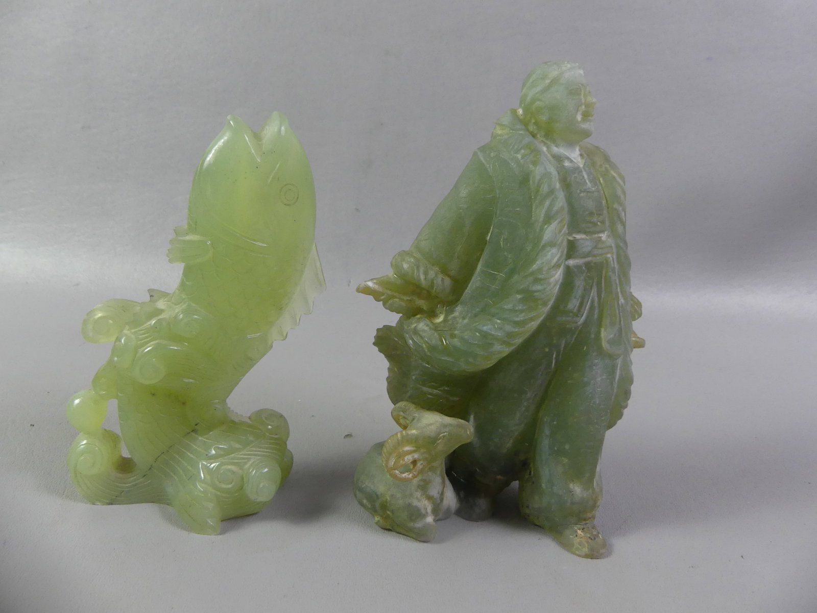 2 CHINESE JADE FIGURINES: Lot 2 old Chinese jade figural items to 7 in tall: Man with horned animal at his feet (some discoloration to surface) and fish rising out of the waves (VG condition).