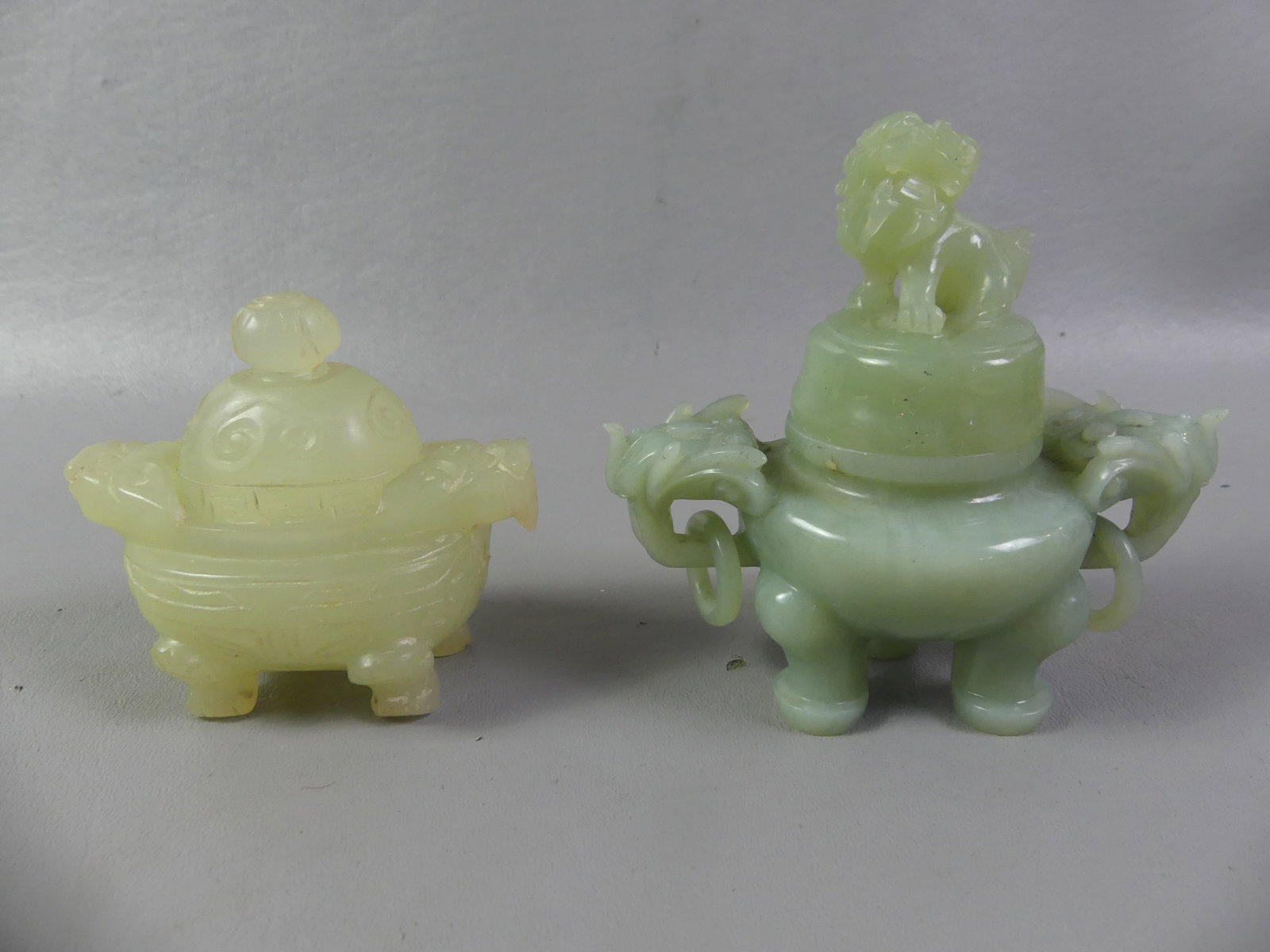 2 CHINESE JADE INCENSE BURNERS: 2 old Chinese jade incense burners with lids to 4 in tall: Green jade with foo lion finial and ringed handles; and pale yellow (chip to handle)