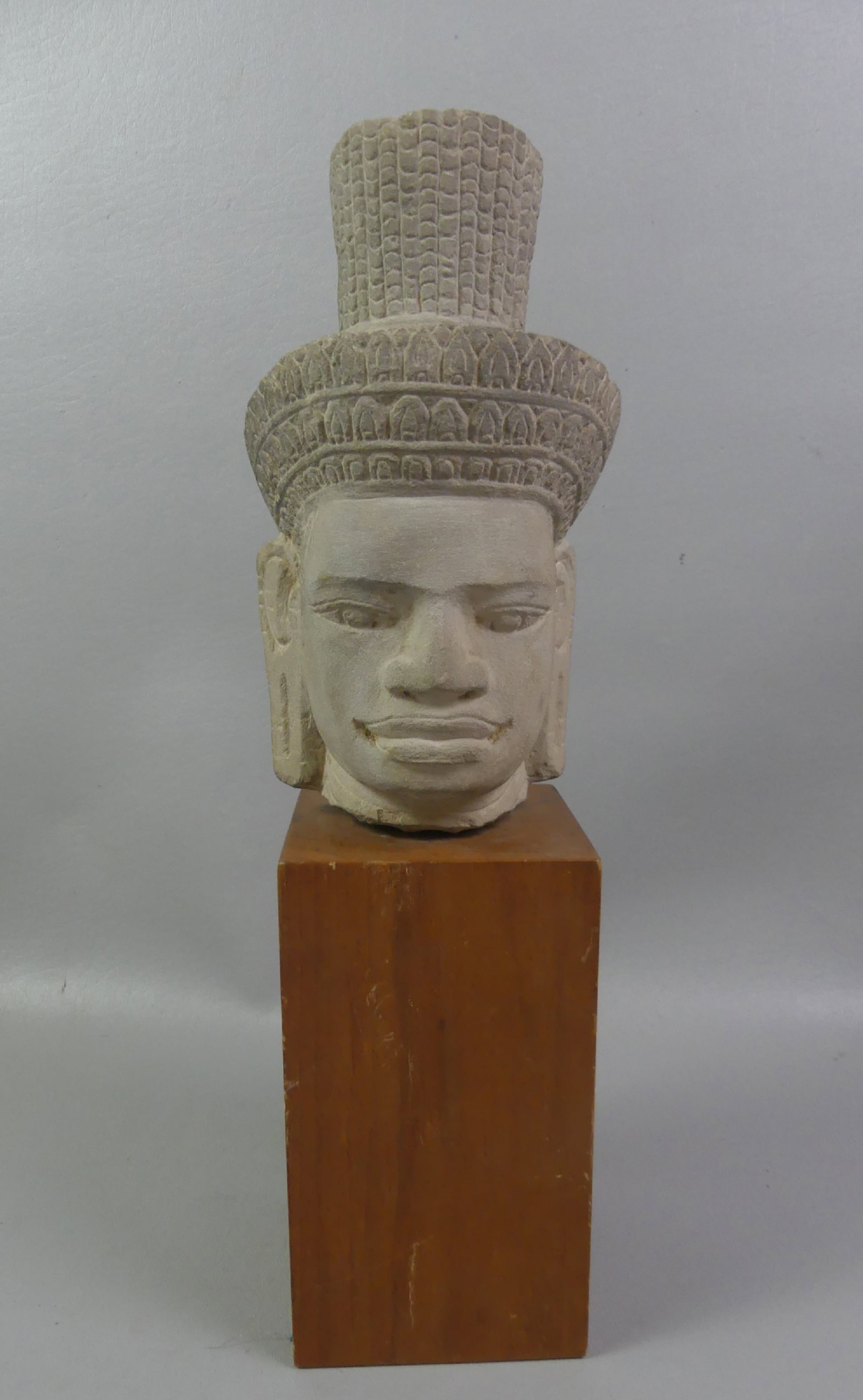 CAMBODIAN STONE HEAD SCULPTURE: Antique carved stone head sculpture on 7 inch wood base attributed Khmer, Cambodia. 16 in tall overall.