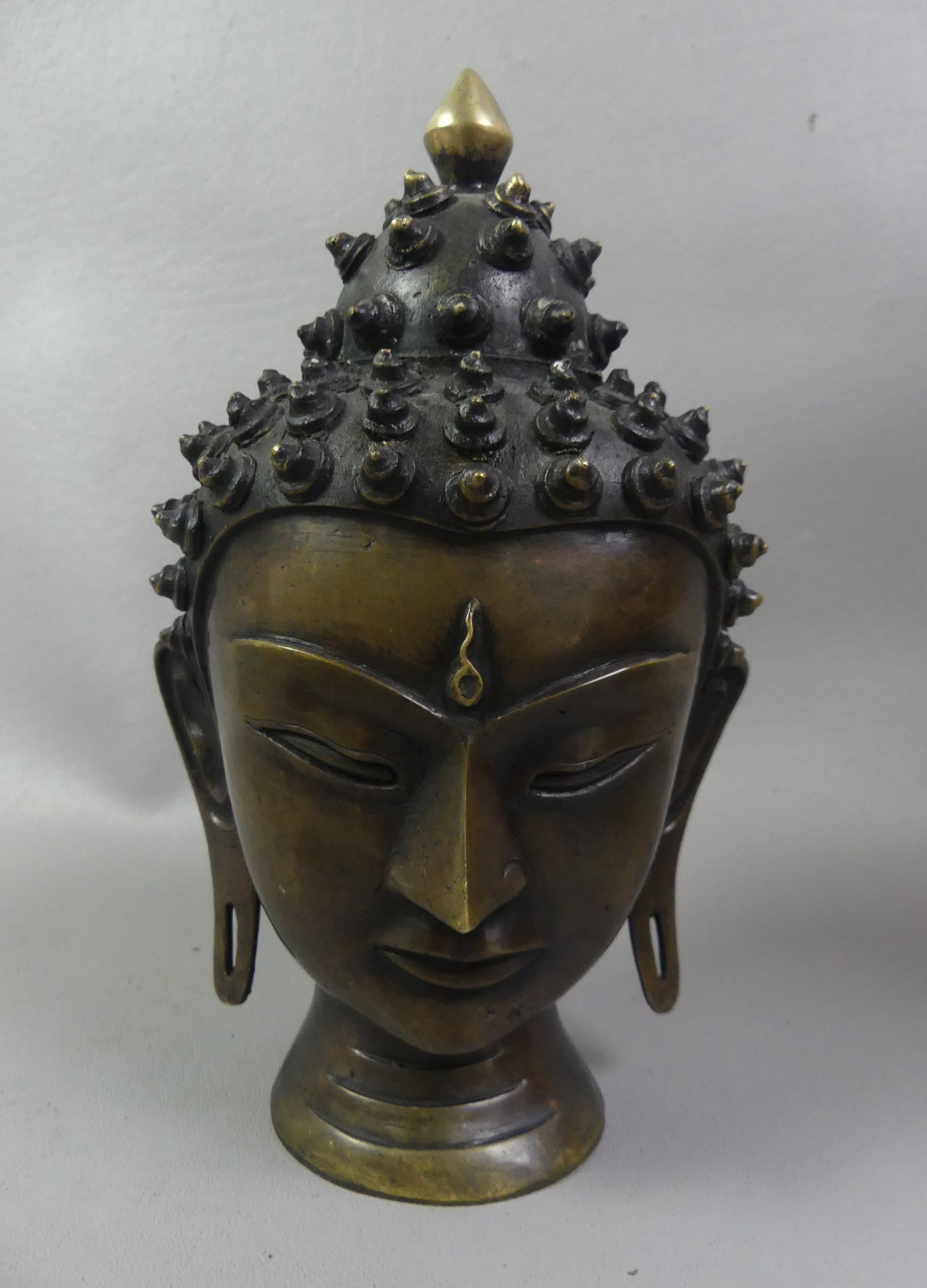 TIBETAN BRONZE BUDDHA HEAD: Old bronze buddha head (no base) attributed Nepal or Tibet. 8 in tall.