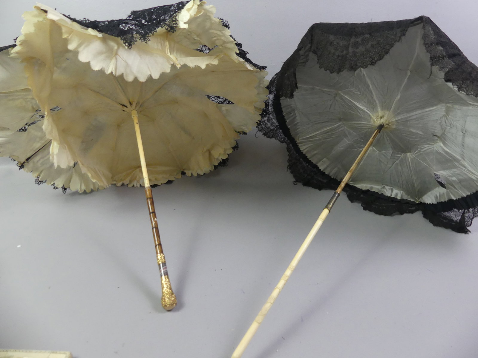 2 ANTIQUE PARASOLS: Lot of 2 antique parasols, one with organic carved handle attributed Japanese; othe rwith replaced bamboo handle with gemstone and gold handle. To 22 x 19 inches.