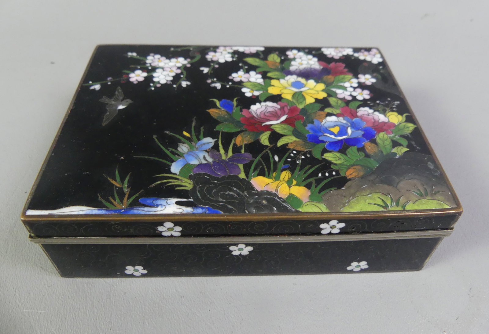JAPANESE MEIJI CLOISSONE BOX: Fine Japanese Meiji period cloisonne box with hinged cover having colorful flowers and bird. Underside has arabesque designs. 5.25 x 4 x 1.5 in high. Good condition, no dents or loss to enamel. Circa