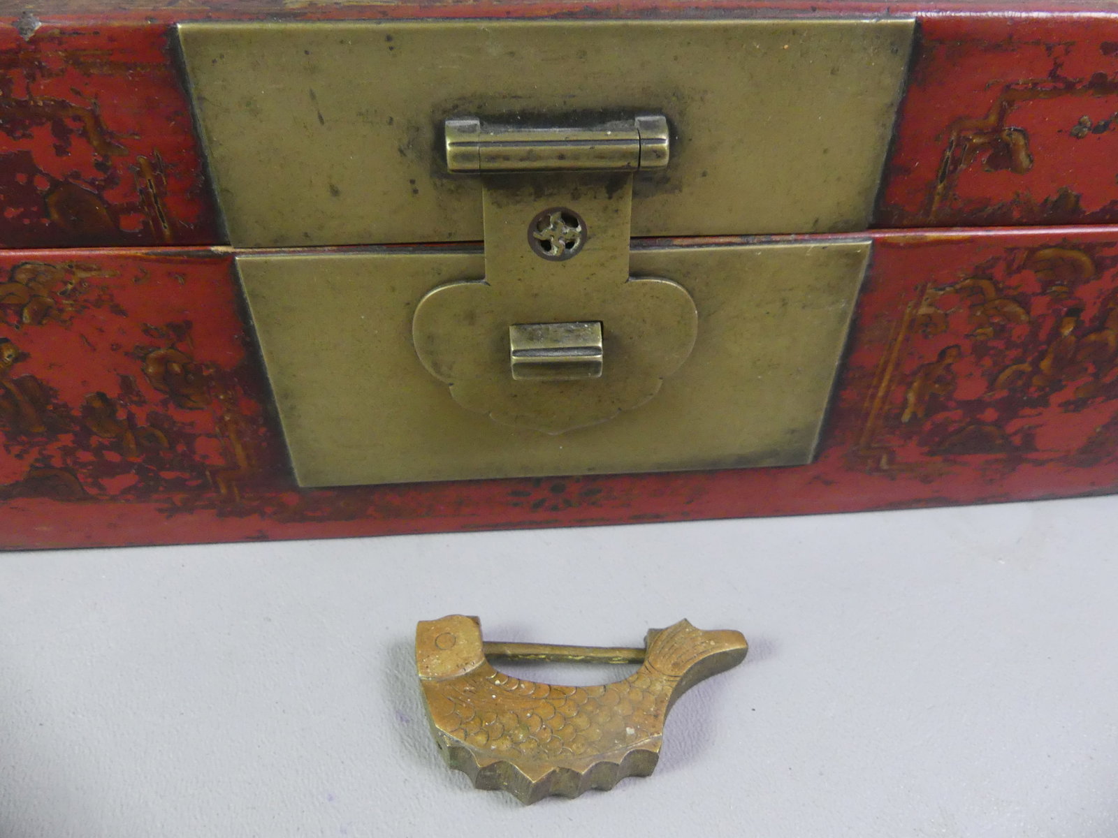 ANTIQUE CHINESE LACQUERED BOX: 19th century Chinese red lacquered and gilt wood box with brass hardware and fish-form key lock. Lid has scenic design with figures. 10.5 x 5.75 x 4 in deep. Some wear to decoration.