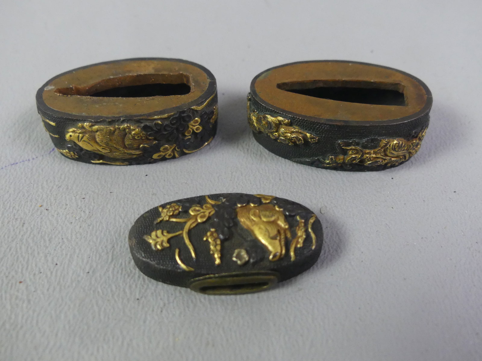 3 JAPANESE SWORD FITTINGS: Lot of antique Japanese sword fittings: 1.25 in oval (pommel?) with landscape and gold inlay; 2 dagger fittings, 1.25 x .75 inches, one with boar and flowers, other with dragon and creature.