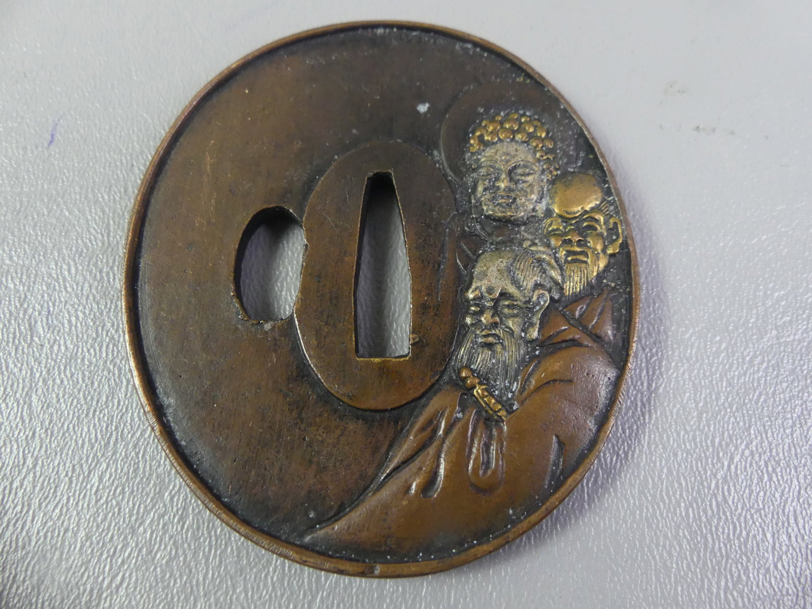 ANTIQUE BRONZE TSUBA - 3 FIGURES: Edo period Japanese bronze tsuba with mixed metal inlay (shakudo) of a sage and two other figures. It has a landscape on back and is signed with Asian characters. 3 x 2.75 inches.