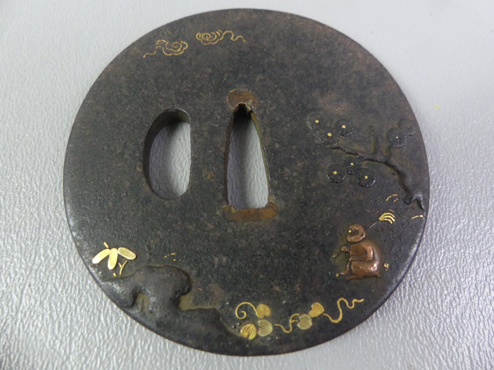 ANTIQUE IRON TSUBA - FISHERMAN: Edo period Japanese iron tsuba with mixed metal inlay (shakudo) of a man fishing in landscape, back has floral design. Unsigned. 2.75 in diameter.