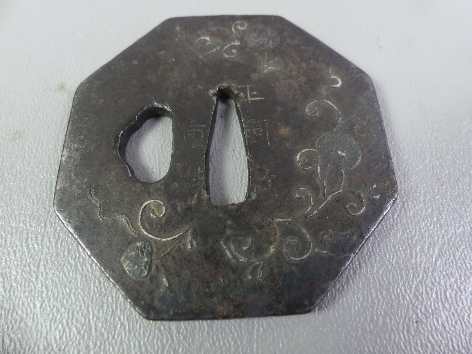 ANTIQUE IRON TSUBA - HEXAGONAL W/INLAY: Edo period Japanese iron tsuba in hexagonal form with silver inlay of flowers (lotus?) and arabesques. Signed with Asian characters. 2.5 in diameter.