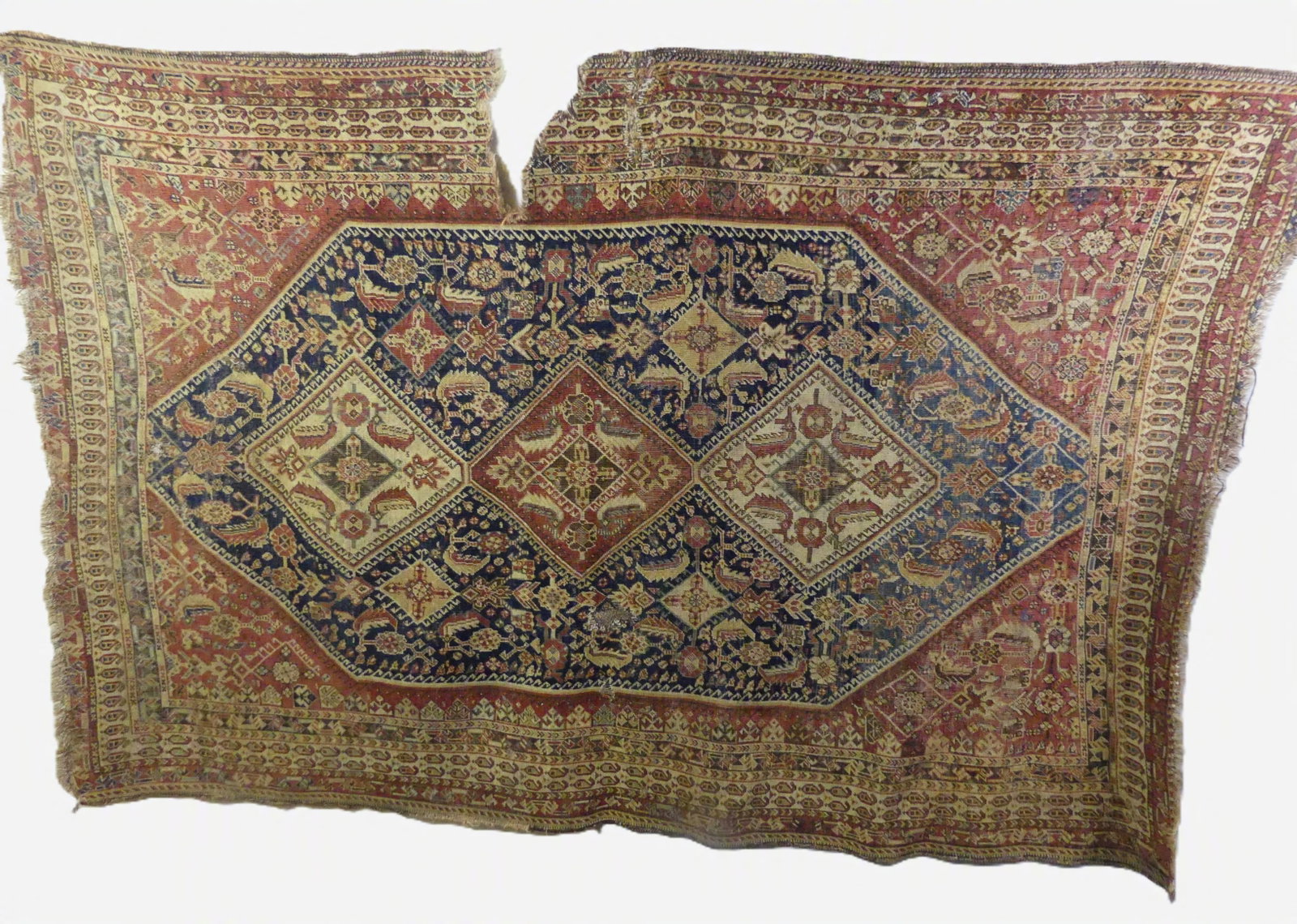 ANTIQUE QASHQAI CARPET: Antique Qashqai rug, 4 ft 7 x 6 ft 10 inches. Has damage, repairs, wear, and 10 inch open tear on edge.