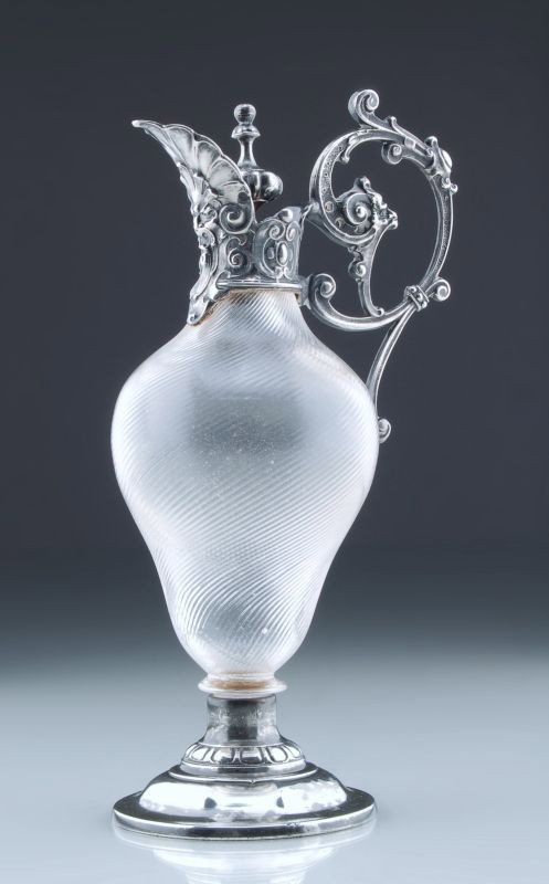 Kleine Karaffe. Um 1890.: Kleine Karaffe. Um 1890. Glass und Weißmetall. Empireform mit balusterförmigen Korpus über montiertem, profilierten Rundstand. Kurzer Hals mit Montierung, hochgezogenem, blattförmigen Ausguß und 