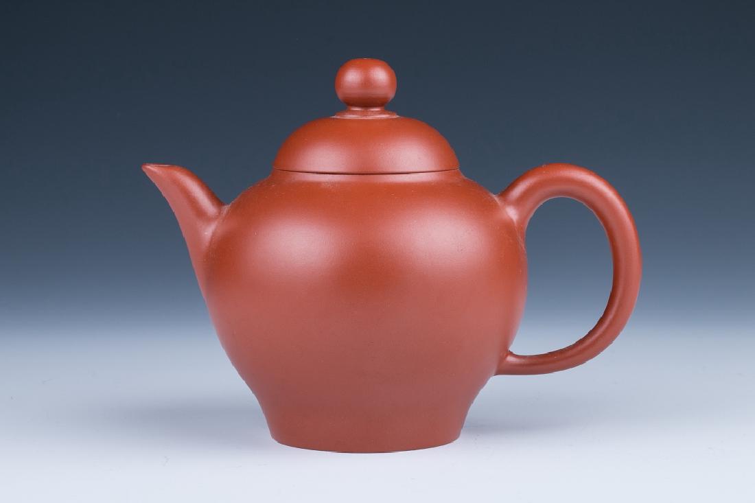 A GLOBULAR ZISHA TEAPOT CHANG YANMING MARK: A zisha teapot, of globular body with curved handle and spout, the base inscribed with four-character Chang Yanming artist seal mark, height 10 cm