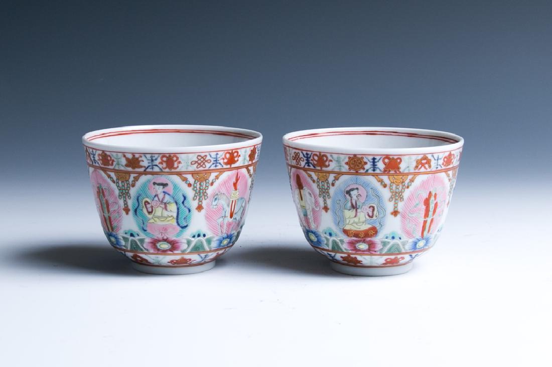 A PAIR OF FAMILLE-ROSE 'BUDDHIST EMBLEMS' CUPS: Each of deep 'U' - shape, supported on a short foot, decorated around the exterior with a parade of auspicious animals and deities of the Qi zheng bao ("Seven Treasures"), each set on a lotus flowerwi