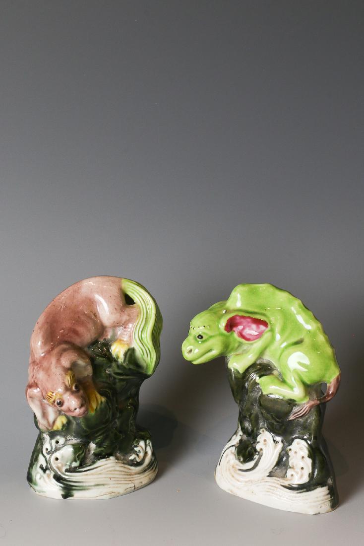 PAIR OF BIG PORCELAIN SEA BEASTS QING: Each modeled with a sea beast in light purple and green resting on a dark green stone above sea waves, each beast with big ears and long tails, the unglazed base reveals the buff ware. H: 11cm & 10.7c