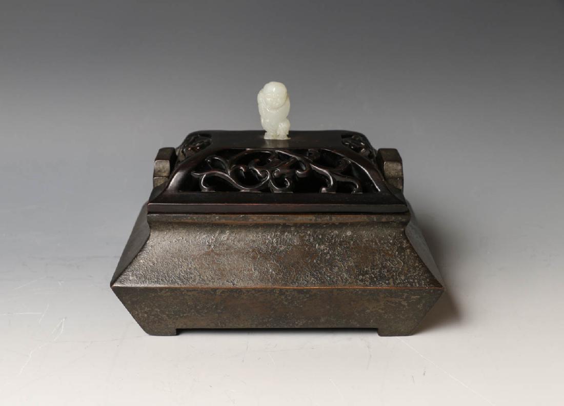 CHINESE BRONZE SQUARE CENSER WITH COVER 17TH/18TH C.: Of compressed square form, supported on four bracket feet with two upright loop handles, accompanied with a fitted pierced wooden cover with jade figural handle, the base with ten-characters Chongzhen