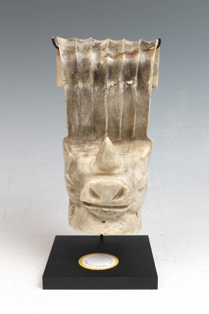 CHINESE CHICKEN BONE JADE ZODIAC HEAD DRESS FINIAL: The head dresser finial carved with the face of a mythical beast, the stone of greyish-brown tone, accompanied with a fitted stand. Provenance: Cowperthwaite family collection.H:20cm