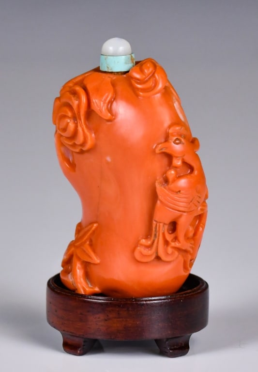 A Coral Carved Snuff Bottle w/Std Qing: A coral carved snuff bottle with flower and bird decoration, comes with stone stopper and wood stand, H:5.5cm Condition report available upon request. Prospective buyers should inspect each lot to sat