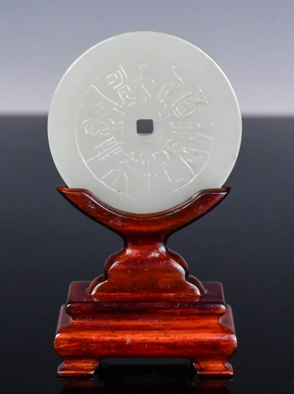 A Celadon Jade Round Plaque w/Std Republican: The plaque of round-shaped with an aperture in the center, carved in low relief with Bagua and ancient Chinese character motifs on each side. D: 5.6cm 民國 青玉雕八