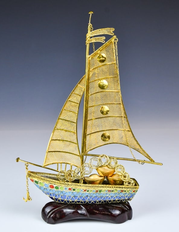 A Gilded Cloisonne Enamel Sailboat Figurine w/Std: Gilt metal filigree with cloisonne enamel decoration along the hull, the ship set with wirework sails adorned with gold coins and decked with miniature gold ingots symbolizing wealth and fortune. H:22