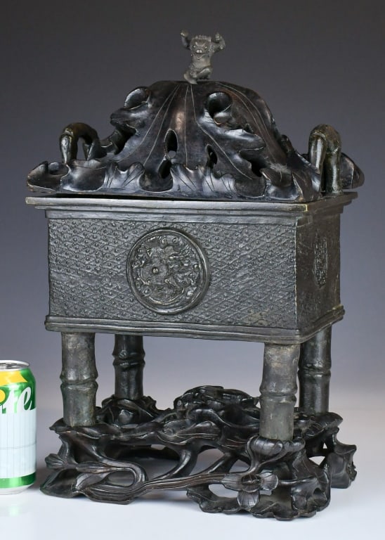 A Ming Style Bronze Double-Handled Censer w/Std: Of rectangular form with loop handles, the cover modelled as a lotus leaf and surmounted by a beast finial, raised on four bamboo-form supports. The body cast with a textured ground and a circular med