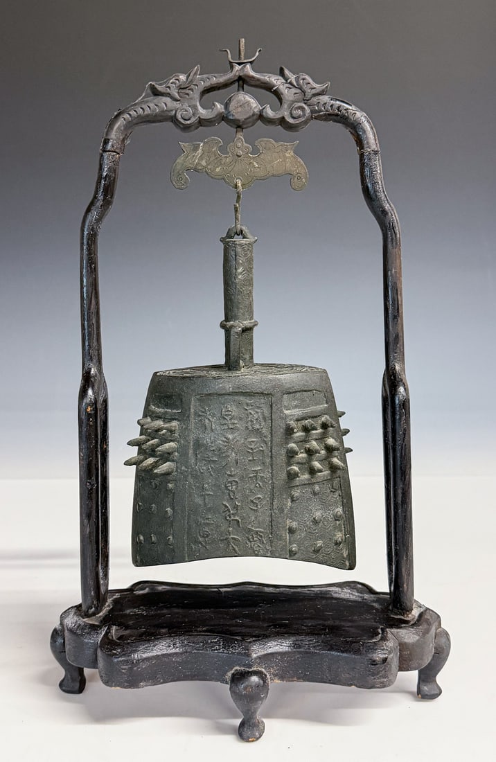 An Archaistic Bronze Ritual Bell Qing: The bell of bo zhong form, cast with a flat mouth and a lenticular cross-section. The exterior is meticulously decorated on each side with thirty-six protruding bosses (mei) arranged in three register