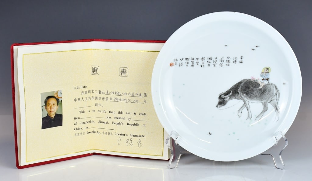Wang XiLiang (1922-2023) Famille-Rose Charger: The shallow circular vessel is finely painted in the center with a pastoral scene depicting a sturdy water buffalo treading softly through a lush landscape. The upper left with artist's inscription an