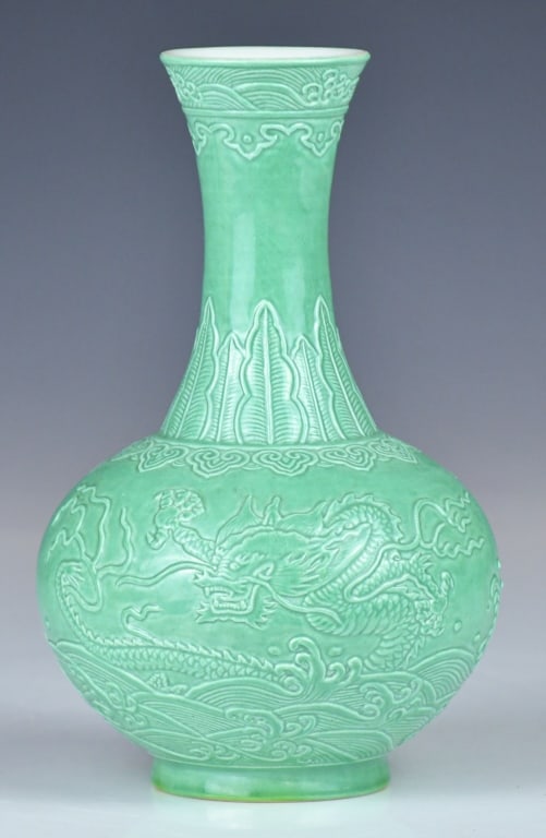 A Relief-Molded Monochrome Green Vase Guangxu Mk: The molded green glazed vase, depicting dragons chasing each other above waves. The base inscised with a six-character Guangxu mark. H:20.5cm 浮雕龍紋綠地賞&#