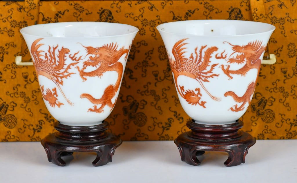 A Pair of Iron Red Cups w/Box w/Std Republican: Each of flared form, the exterior decorated with dragons and phoenixes, the interior base painted with a floral medallion, come with wood stands. H: 6.4cm, D: 7.8cm 民國