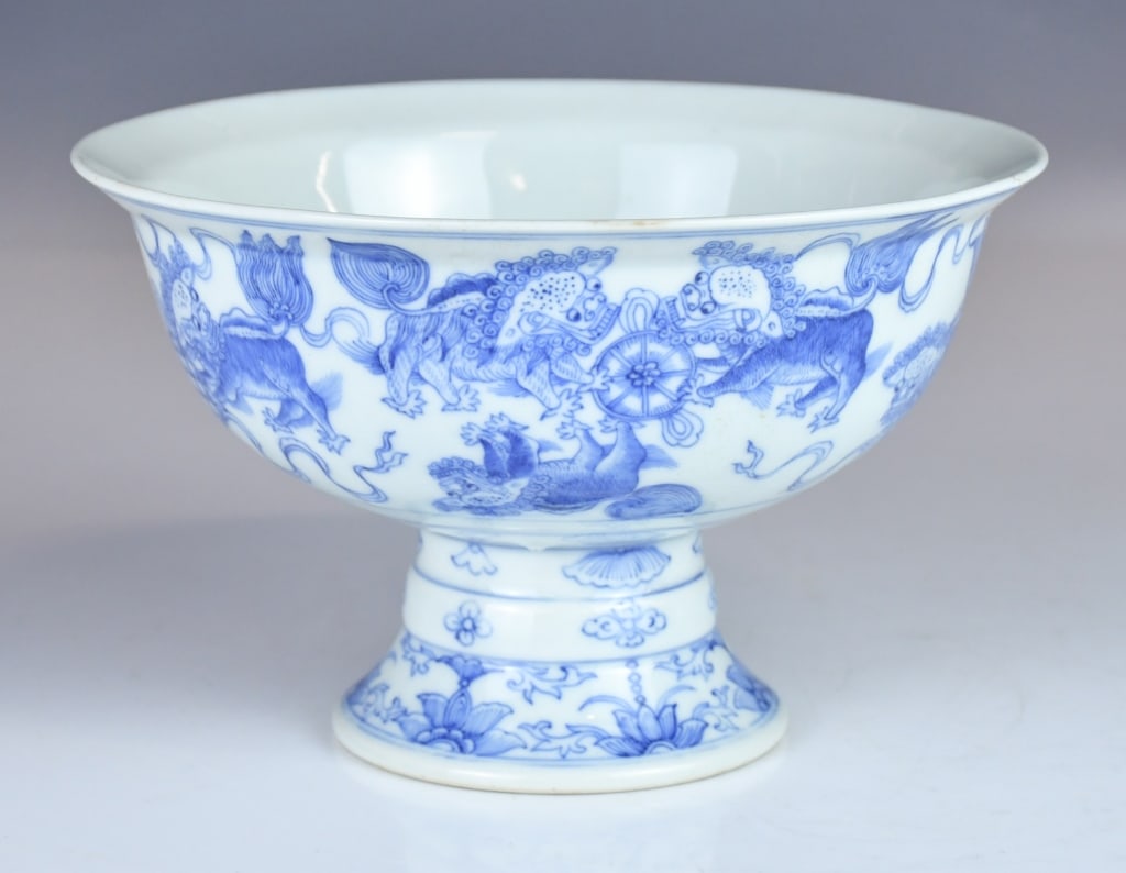 A Blue & White Stem Bowl Qing: The deep bowl raised on a hollow stem foot, the exterior painted with lions playing with brocade balls. The stem further decorated with floral patterns. H:11.5cm, D:18.2cm 清