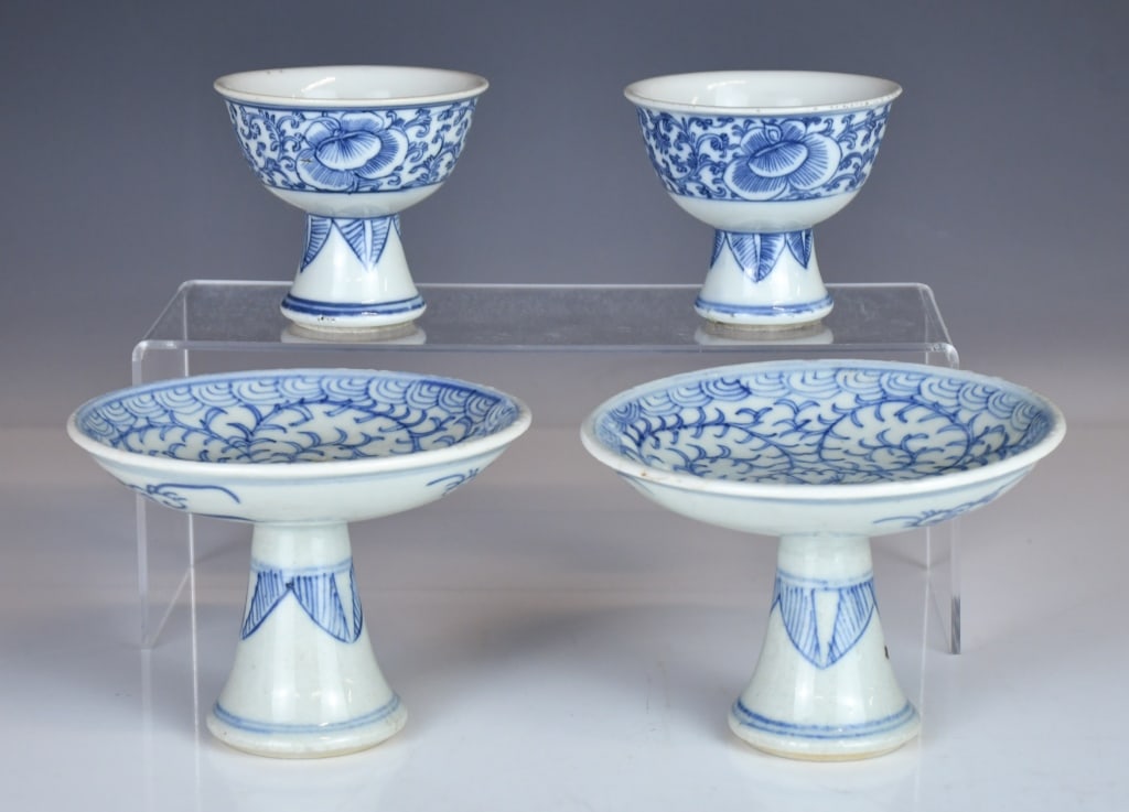 2 Blue & White Stem Dishes & 2 Stem Cups Qing: Comprising a pair of stem dishes and a pair of stem cups, each with a shallow bowl raised on a hollow stem foot, decorated with scrolling floral motifs. Dish D:13.2cm, H:9.5cm each; cup H:7.5cm each &