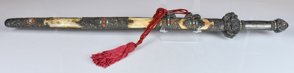 An Embellished Sword & Scabbard Republican: This ceremonial sword with a hilt featuring intricate metalwork-bound grip. Both the hilt and scabbard are heavily decorated with coral and turquoise stones set into elaborate silver filigree. The sca