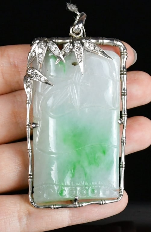 A Jadeite & Diamond Bamboo Pendant: The rectangular jadeite plaque carved with a bamboo motif. The plaque is set within a conforming openwork frame of polished silver, embellished with diamonds set into foliate bamboo leaf accents