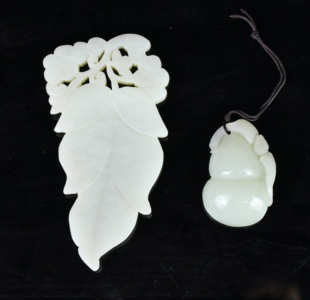 A Group of 2 Jade Carvings Qing: Comprising a pendant carved in the form of a double gourd issuing leafy tendrils, overall of celadon tone, 4.2x2.8cm; together with a jade plaque carved as a leaf suspending from scrolling stems