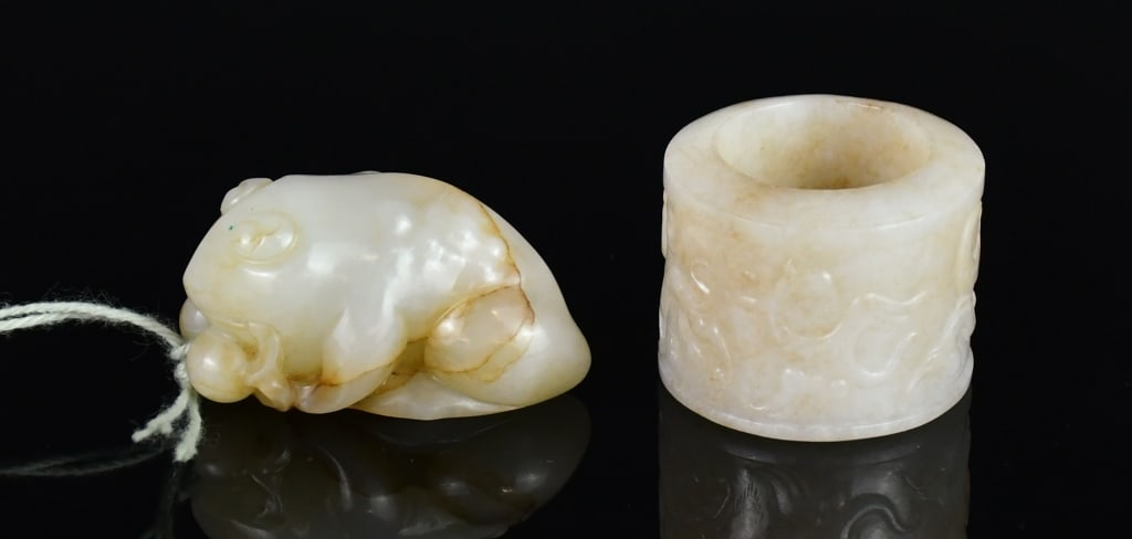A Group of 2 Jade Carvings Qing: Comprising two jade carvings. The first carved as a recumbent toad, the stone of creamy yellowish-white tone suffused with russet veining, 2.8x4.6cm. The second worked as a ring, carved in low