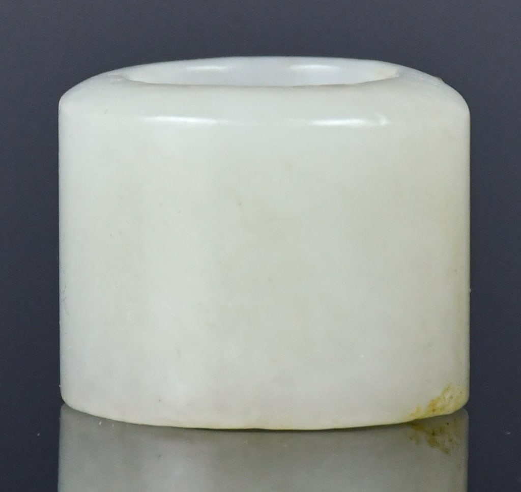 A White Jade Thumb Ring Qing: The thumb ring of plain cylindrical form, the stone of overall white tone. D: 8.5cm, H: 2.8cm 清 白玉扳指 Click