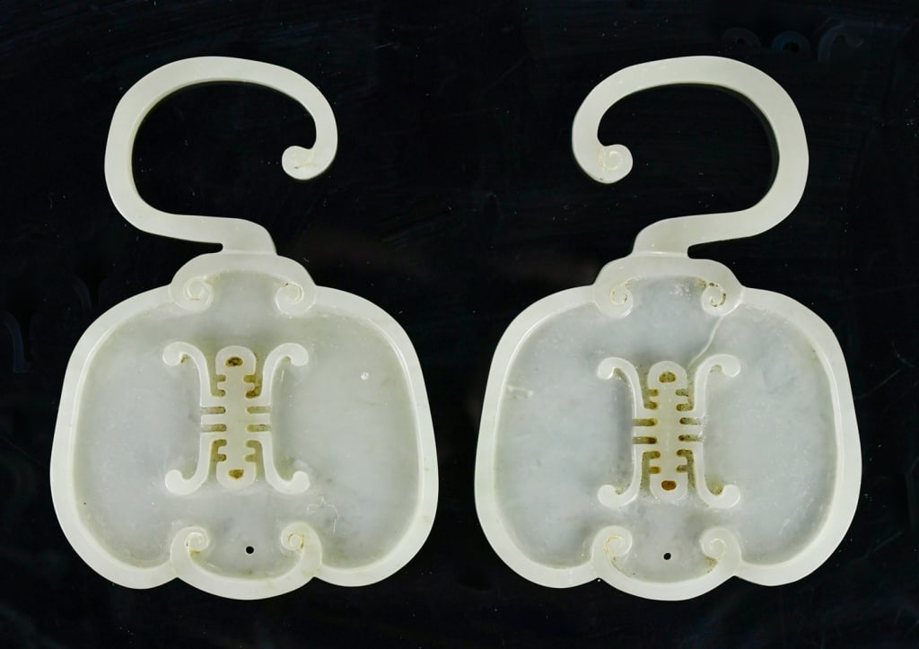 A Pair of Jade Carved Plaques 19thC: A pair of celadon jade plaques decorated with swirls and a Chinese Shuo motif at the center. L: 11.9cm, W: 8.3cm 19世紀 玉帶鈎珮對 Click here for