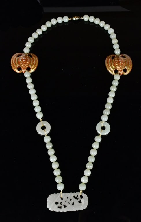 A Jade Bead Necklace with Pendants Qing: Composed of a strand of celadon jade beads, interspersed with various pendants, including openwork jade plaques and carved elements, all carved in the form of bats. L: 40cm 清