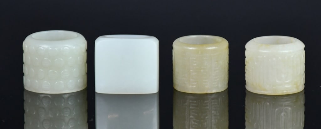 Group of 4 Jade Carved Thumb Rings Republican: Comprising four thumb rings of varying sizes and colours. Largest D:3.2cm 民國 玉扳指一組4件 Click here for natural light photos