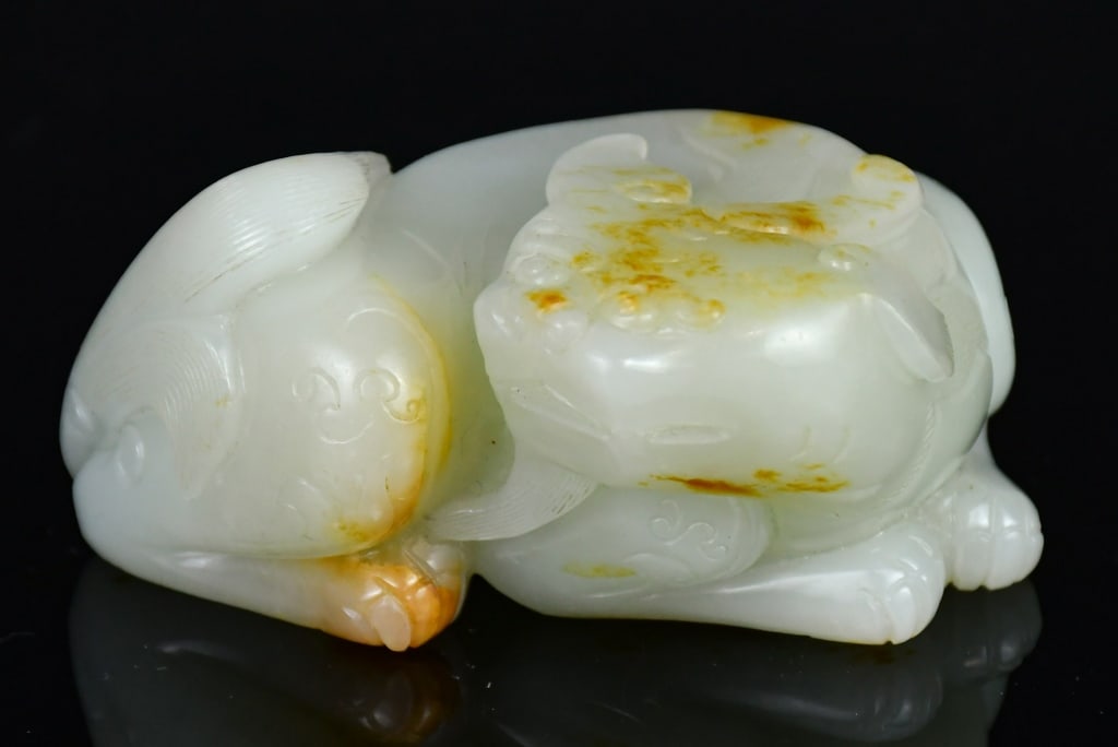 A White Jade Carved Mythical Beast Republican: Depicting a recumbent mythical beast, the stone overall of light celadon tone with russet areas. 8.7x7.4cm 民國 白玉雕瑞獸擺件 