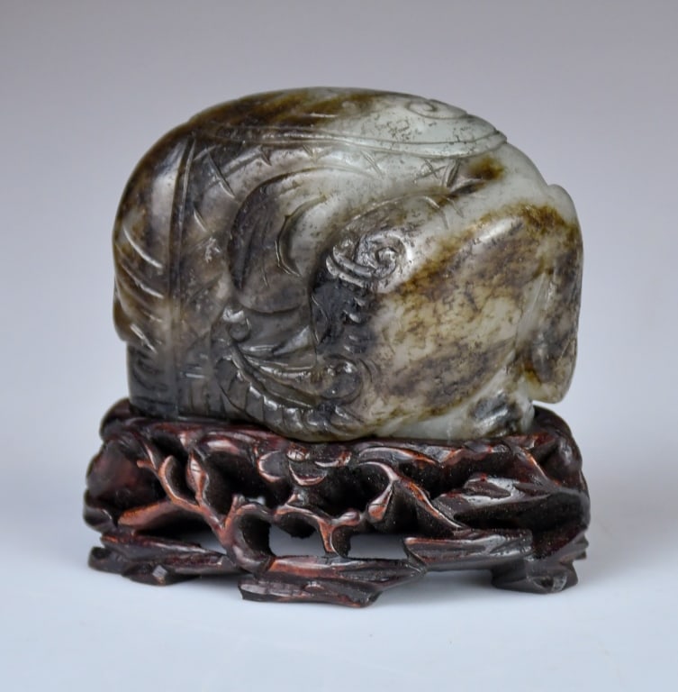A Jade Carved Elephant w/Std Qing: Depicting an elephant draped with a caparison, the stone overall of light celadon and russet tones; comes with a wood stand. 4.5x6.3cm. 清 玉雕象擺件