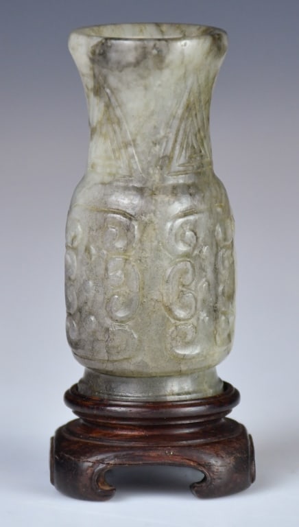 A Small Jade Carved Vase w/Std Ming: Of baluster form, rising from a short spreading foot to a waisted body and flaring neck, the exterior carved in low relief with scroll motifs. The stone of a dark celadon tone. H: 7.1cm 