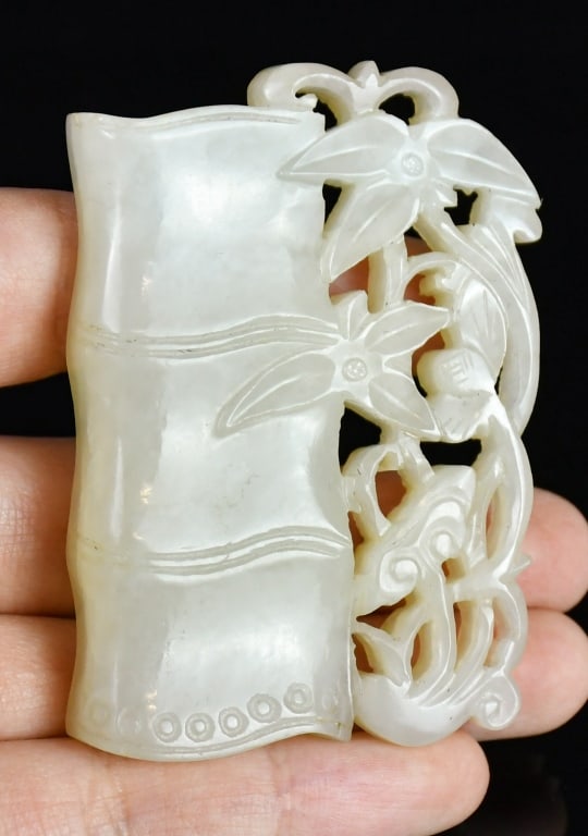 A Jade Carved Bamboo Qing: Of bamboo-section form, carved along one side in openwork with flowering blooms and scrolling foliage, the stone of a pale celadon tone. 6.2x4.3cm 清