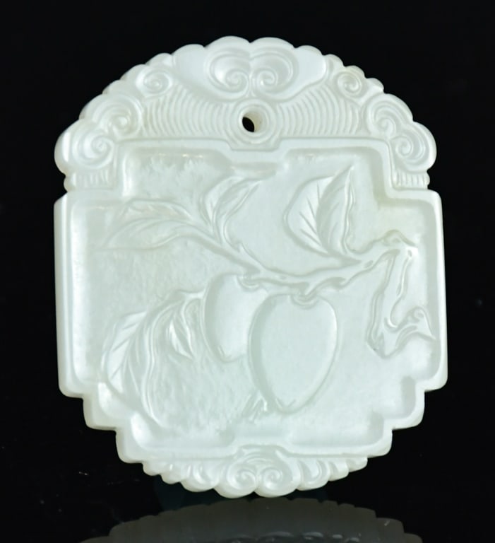 A White Jade Incised Plaque Qing: Of rectangular form with shaped edges, one side carved in low relief with a fruiting branch, the upper border decorated with ruyi-form cloud scrolls, the reverse incised with Chinese characters;