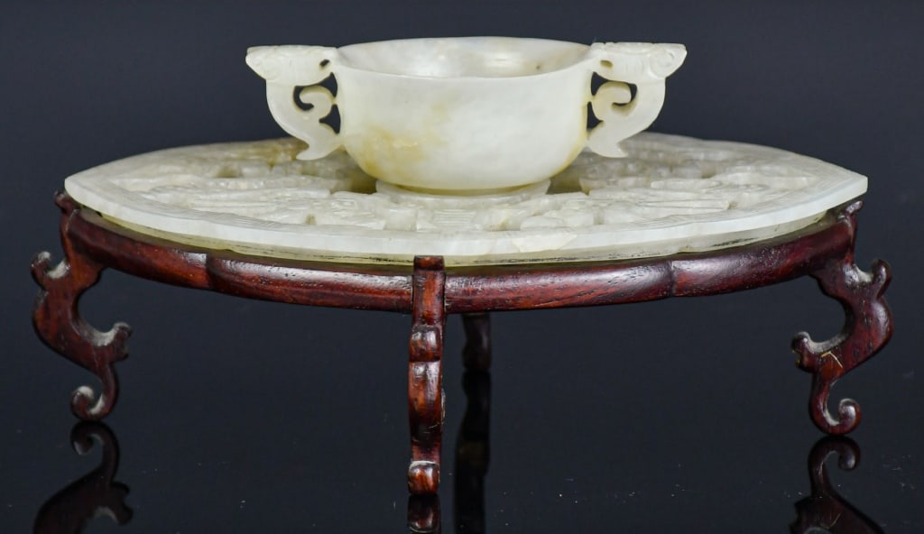 A Jade Carved Dragon Cup & Saucer w/Std Qing: Comprising of a jade cup with beast-head handles and a shallow jade saucer carved in low relief with lotus blossoms, pods, and roots, the stone of pale celadon tone with light russet shading. cup 