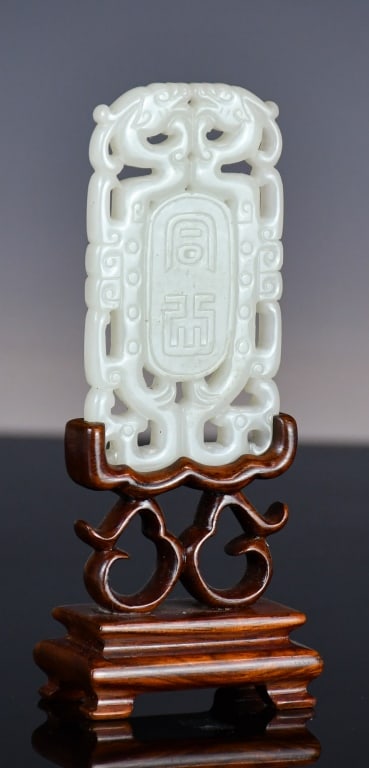 A White Jade Carved Dragon Plaque w/Std Qing: A reticulated white jade plaque, center incised with Chinese characters, with dragons flanked each side, 7.7x4cm, comes with a wood stand. 清