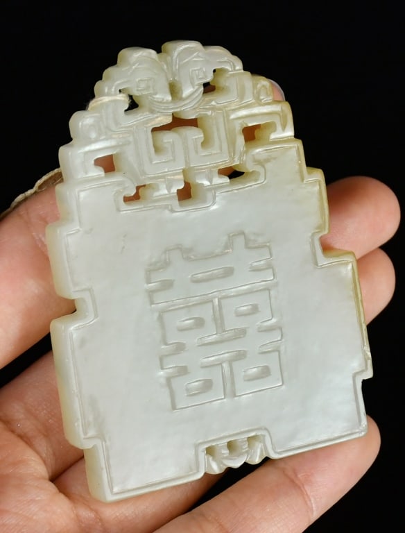 A Jade Carved Plaque Qing: With openwork carving at the top, one side carved with flowers, the other with a Chinese "Xi" character, the stone overall in a pale celadon tone. 6.6x4.9cm 清