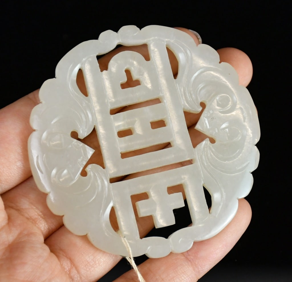 A Reticulated Jade Plaque Qing: Of circular form, carved with bats surrounding a Chinese "Shou" character at the centre, D: 5.8cm 清 透雕福壽紋圓玉珮 Click here for