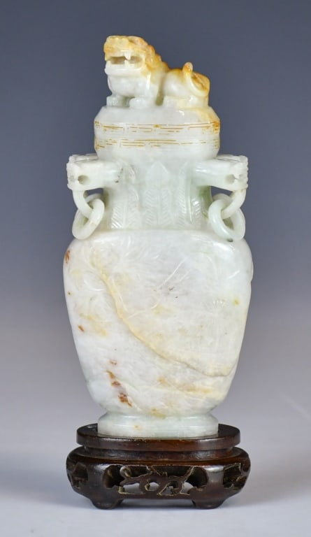 A Jadeite Carved Cover Vase w/Std 1950-70s: The vase cover with a beast finial, flanked by set of 4 loop handles around the neck, the body decorated with landscape scene, the stone overall in milky white tone with russet inclusions.H: 15cm 
