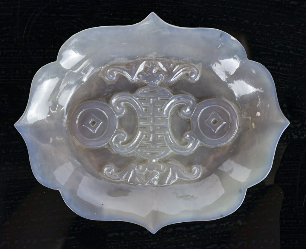 A Carved Agate Lobed Dish Republican: The shallow agate dish is translucent and worked with an eight-lobed outline. The interior is carved in low relief with a central shou character, framed by a pair of coin motifs and accompanied by two