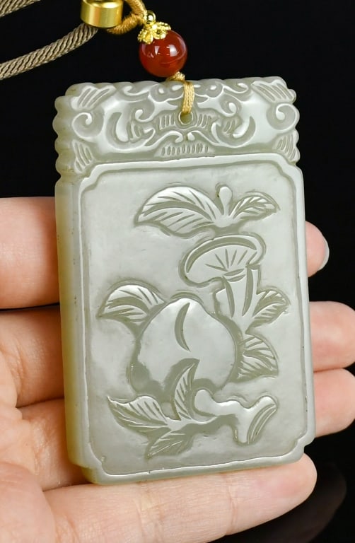 A Celadon Jade Carved Plaque Republican: A rectangular jade plaque, one side incised a peach and Lingzhi, and the other side with a plant and a bird, 6.7x4.4cm 民國 青玉仙桃靈芝紋方